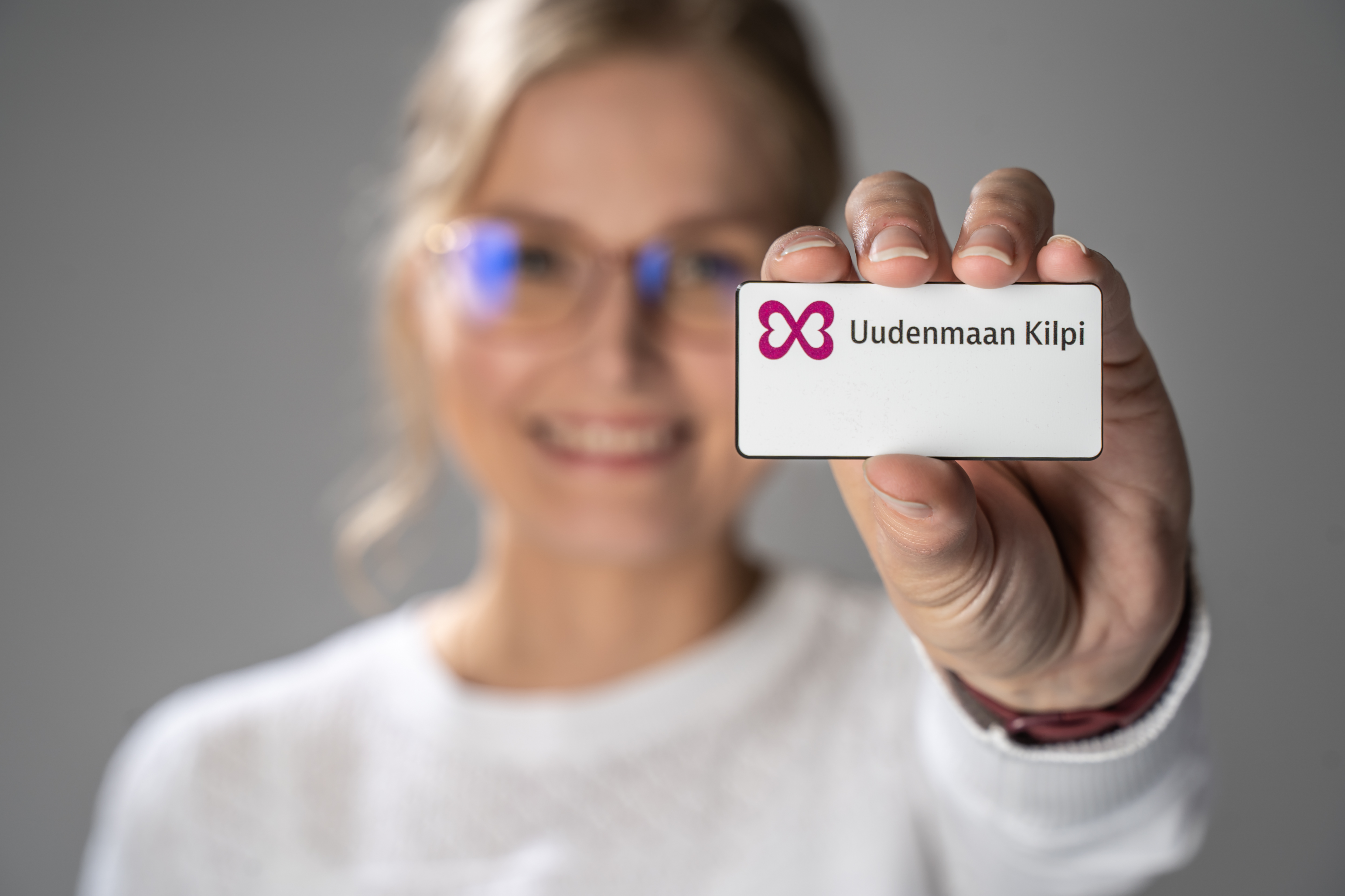 Kuvassa nainen pitelee pientä nimikylttiä, jossa lukee Uudenmaan Kilpi